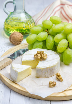 Soft brie cheese with sweet grapes and nuts closeup