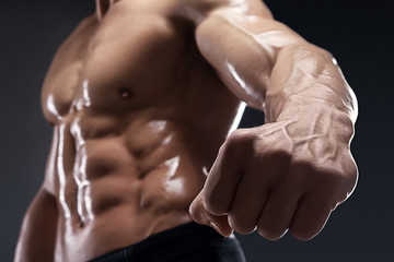 Handsome muscular bodybuilder shows his fist and vein.