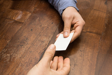 mani che si scambiano un bigliettino da visita