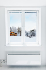 Wooden house covered  snow seen through the window