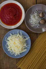 Spaghetti, tomato sauce and spices on a wooden board (close up)