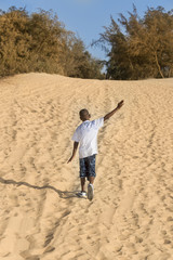 Afro boy walking in the sand, ten years old 