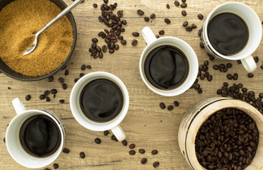 4 Black coffees with beans and sugar on wooden sufrace from abov