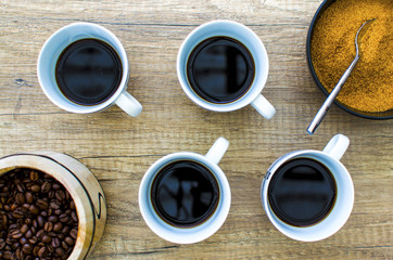 4 Black coffee cup with beans and sugar on wooden surface from a