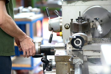 Blue-collar worker doing manual labor with a lathe - obrazy, fototapety, plakaty