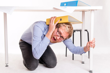 Man in under a desk during the earthquake