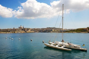 Naklejka na ściany i meble The view on Valletta and sail yacht with Ukrainian flag in sunse