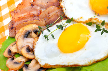Bacon with sunny side up eggs served with toasts on a orange nap