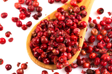 red peppercorns in wooden spoon isolated