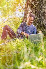 Obraz premium A nice looking grey hair man is sitting against a tree in the gr