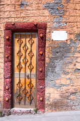 Old colorful wooden door with wrought iron grill.