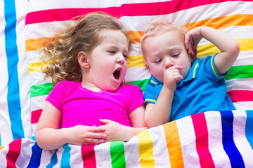 Fototapeta na wymiar Children sleeping under colorful blanket