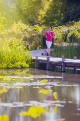 Fototapeta na wymiar A good looking woman is running on the pontoon of a lake