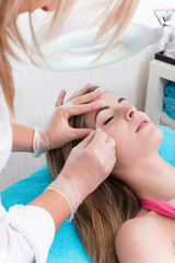 Woman getting tweezing eyebrow