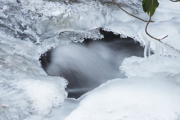 Frozen creek with water running beneath the ice.