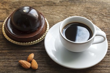 Coffee with chocolate cake and almonds on wood background