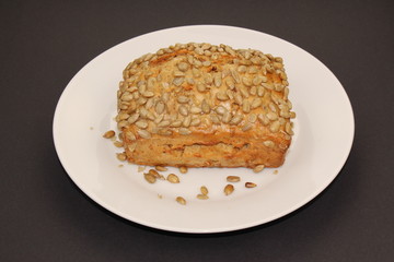 An isolated bread with sunflower seeds on a white plate