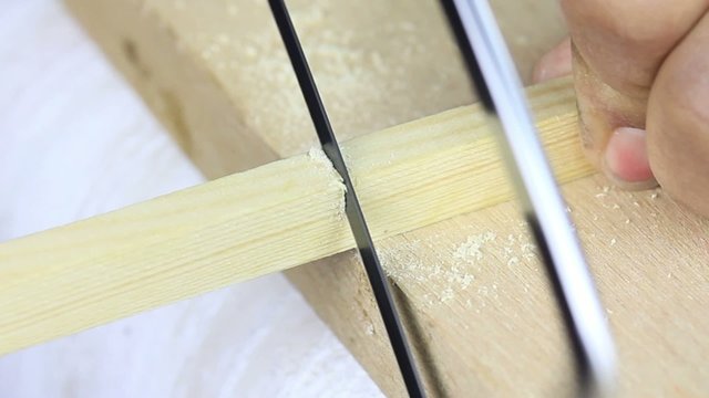 piece of plank is cut by hand using a back saw.