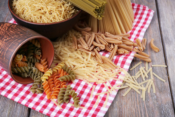 Fototapeta na wymiar Different types of pasta on napkin on wooden background