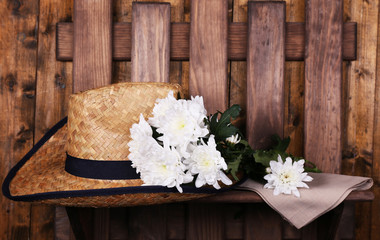 Hat with flowers on wooden background