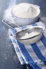 Sifting flour through sieve on wooden table, closeup