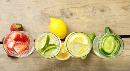 Glasses of different home made freshness healthy vitamin-fortified water on wooden table