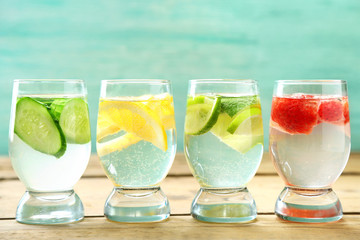 Glasses of different home made freshness healthy vitamin-fortified water on wooden table
