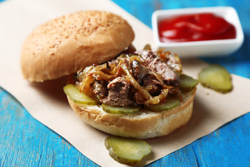 Tasty sandwich on paper napkin, on wooden table background, close-up Unhealthy food concept