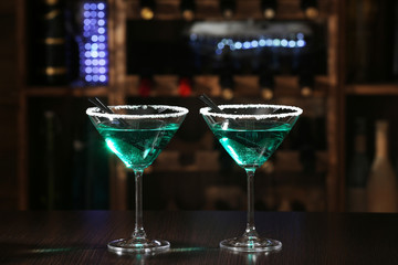 Glasses of cocktails on bar background