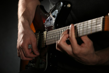 Fototapeta premium Young man playing on electric guitar close up