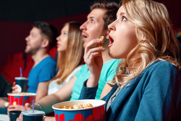 Excited woman with popcorn in cinema  - obrazy, fototapety, plakaty