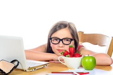 a little girl sitting at his desk with a bowl of strawberries an