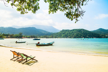 Fototapeta na wymiar Lounge chairs on a tropical beach at summer