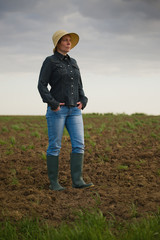 Naklejka na ściany i meble Female Farmer Standing on Fertile Agricultural Farm Land Soil