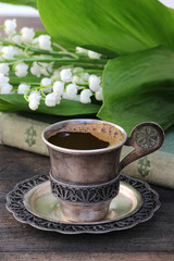 A cup of coffee, lilies of the valley, the old book