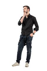 Naklejka premium Young cool trendy man touching his beard looking away.