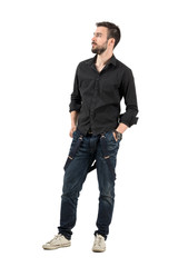 Naklejka premium Serious young man with hands in pocket looking up