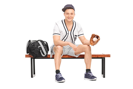 Sportsman holding a baseball seated on bench