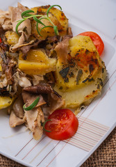 Potato gratin with fresh tomatoes on a white plate