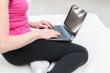 Naklejka premium Woman sitting on a carpet using a computer