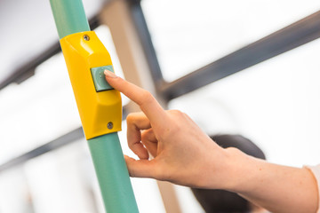 Young woman pressing stop request button on the bus