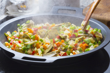 Wood spoon mixing veggies on a pan