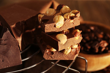 Stack of chocolate with nuts on wooden table, closeup