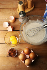 Preparation cream with eggs in glass bowl on wooden background