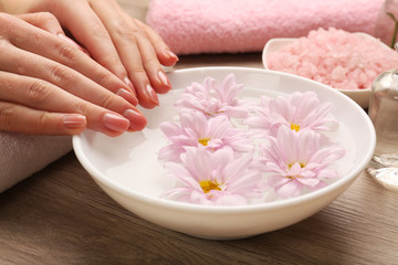 Obraz na płótnie Canvas Female hands and bowl of spa water with flowers, closeup