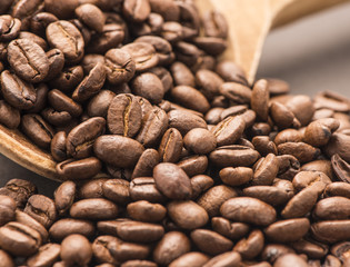 Close up of dark coffee beans on a wooden spoon