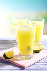 Glasses of cocktails on wooden table on bright blurred background