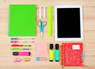 Digital tablet with stationery on wooden background