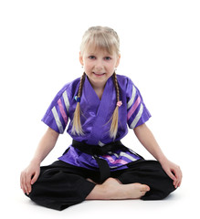 Little girl in kimono doing exercises isolated on white