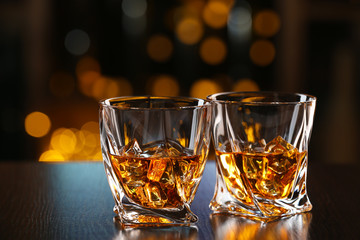 Glasses of whiskey on bar background